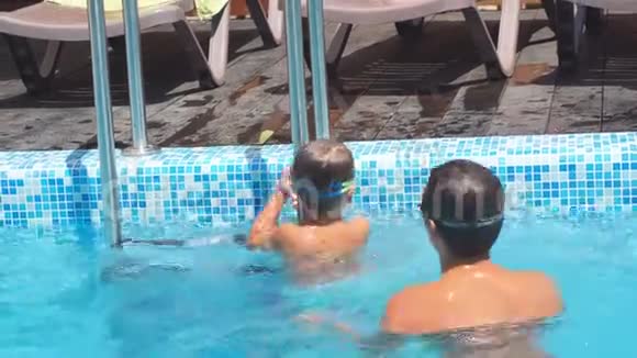 孩子和他的小男孩弟弟在游泳池里玩得很开心慢动作一家人夏天在游泳池里玩视频的预览图