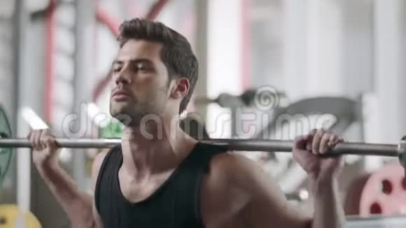运动员在健身俱乐部用杠铃训练蹲操视频的预览图