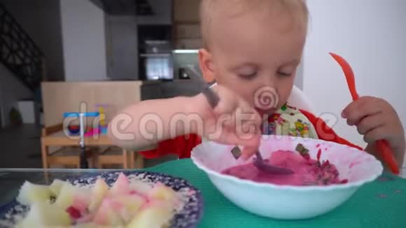 可爱的小男孩用两个勺子吃甜菜根汤和土豆视频的预览图