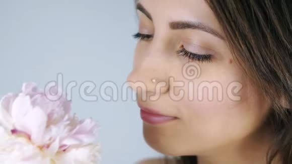 年轻的女人嗅着粉红色的花视频的预览图