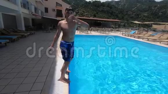 男孩做了一个翻转动作缓慢地潜入游泳池视频的预览图