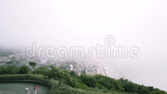在夏季沿海线和被浓雾覆盖的城市的鸟瞰图行动从城市的上方看视频的预览图