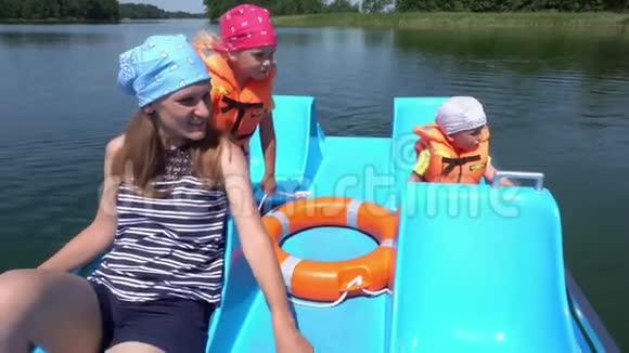 年轻的母亲带着孩子男孩和女孩在双体船上玩得很开心万向节运动视频的预览图