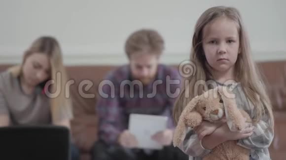 肖像小悲伤不快乐的女孩手里拿着玩具看着镜头年轻女子用手机打字视频的预览图
