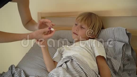 一个生病的小男孩躺在床上的超慢镜头母亲用精油男孩的胸部涂抹药膏婴儿流感视频的预览图