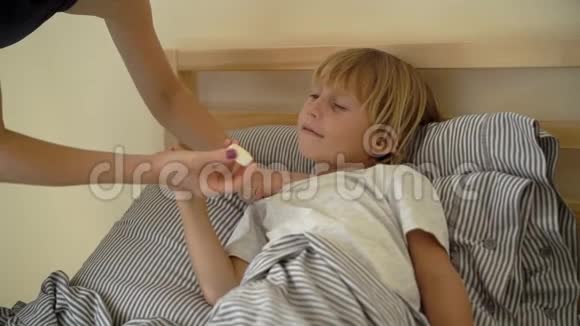 一个生病的小男孩躺在床上的超慢镜头母亲用精油男孩的胸部涂抹药膏婴儿流感视频的预览图