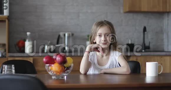 可爱的女学生坐在桌子旁露出一个漂亮的红苹果视频的预览图
