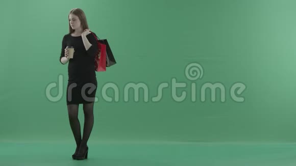 穿着黑色小裙子的漂亮女人正在喝咖啡或茶拿着她的购物袋她站在左边视频的预览图