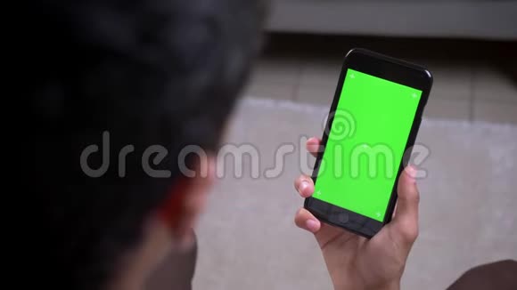 特写后景拍摄印度男性手拿着绿色屏幕的手机垂直在室内公寓视频的预览图