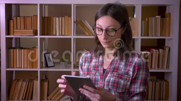 用平板电脑拍摄年轻迷人的女学生戴眼镜的特写镜头用绿色屏幕拍摄微笑视频的预览图
