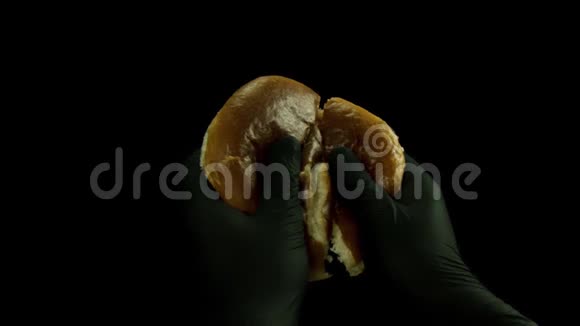 在黑色的烹饪手套中把面包分成两块在黑色的背景上隔离开来库存数据视频的预览图