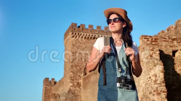 微笑的时尚背包客游客妇女在中世纪城堡放松背景中镜头视频的预览图