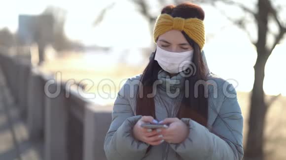 戴着面具的年轻女子在智能手机上发短信视频的预览图