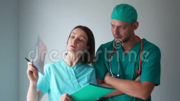两名医生一名男子和一名妇女正在检查一张病人的X光照片医务人员讨论x光结果视频的预览图