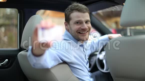 年轻男子坐在车里用拇指上的标志显示他的新驾照视频的预览图
