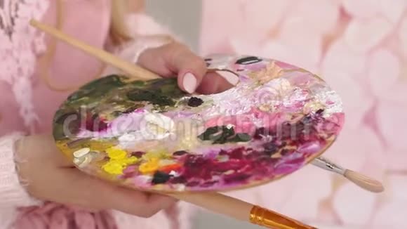 特写的女孩拿着一个大调色板的油漆和刷子画画视频的预览图