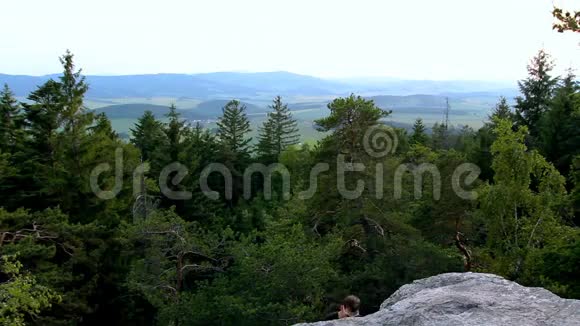 戴墨镜的年轻人爬上捷克风景中的石岩视频的预览图