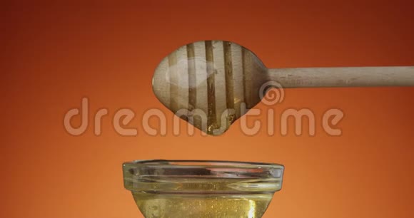 蜂蜜是从一个蜂蜜勺子滴到玻璃碗与兵马俑背景的特写慢动作镜头健康的概念视频的预览图