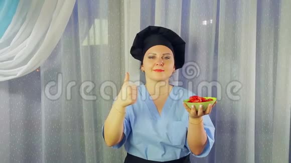 女人穿着围裙做饭微笑着手里拿着盘子里的樱桃番茄用手展示课堂视频的预览图