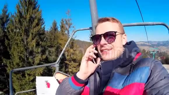 年轻人用手机说话乘缆车在美丽的山脉和视频的预览图