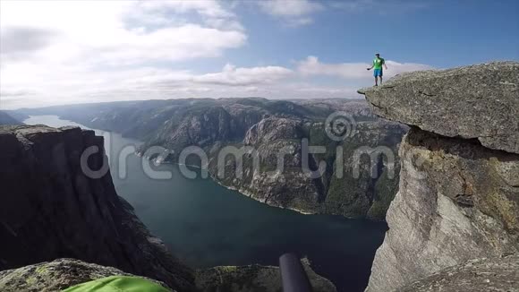 快乐的人跳在高高的悬崖边上背景是挪威的峡湾视频的预览图
