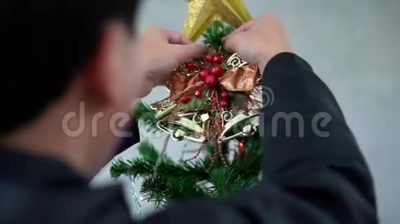 一个年轻人在新年前用五颜六色的花环球和圣诞灯装饰圣诞树视频的预览图