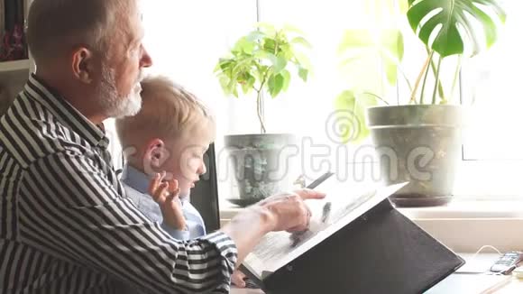 美丽的祖父给他的孙子看他的家庭相册家庭价值视频的预览图