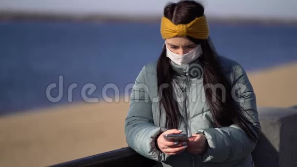 戴着面具在智能手机上发短信的年轻女子视频的预览图
