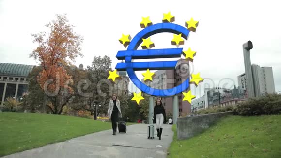 两个年轻漂亮的女人在欧洲联盟的图标下在城市公园散步视频的预览图