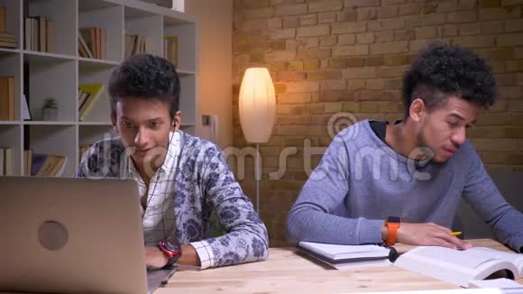 印度男性使用笔记本电脑开心地微笑着听音乐的特写镜头和非裔美国人视频的预览图