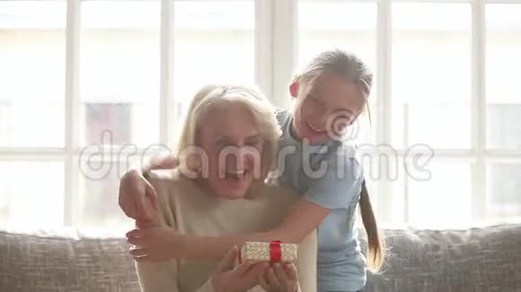 孙女惊喜地拥抱快乐的老祖母送生日礼物视频的预览图