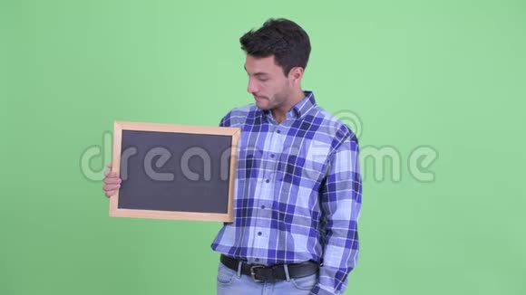一位年轻的西班牙裔男子扶着黑板竖起大拇指视频的预览图