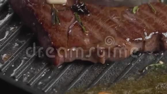 厨师在美味多汁的牛肉牛排上倒入油配调料和大蒜视频的预览图