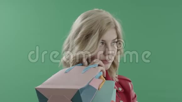 穿着红色夹克的漂亮女士带着袋子看着绿色的屏幕视频的预览图