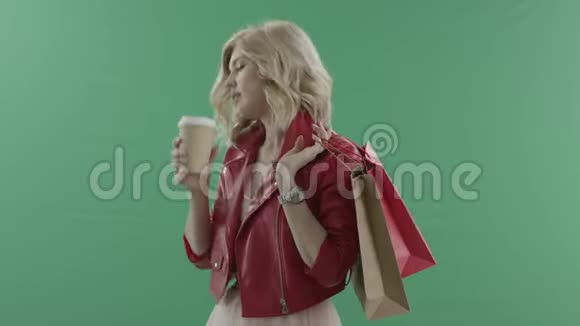 迷人的女人在绿色屏幕上购物时喝咖啡视频的预览图