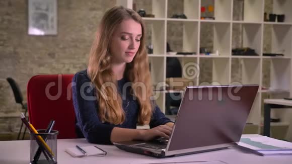 白种人金发女商人在办公室里专心地用笔记本电脑工作的肖像深深地流露出喜悦之情视频的预览图