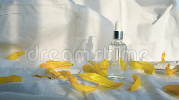 白色背景和黄色花瓣上的一瓶血清概念有保湿血清的漂亮瓶子视频的预览图