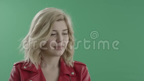 穿着红色夹克的漂亮金发女人在绿色屏幕上摆姿势视频的预览图
