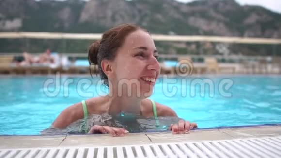 快乐的女孩在游泳池里她的腿在缓慢地摆动很有趣视频的预览图