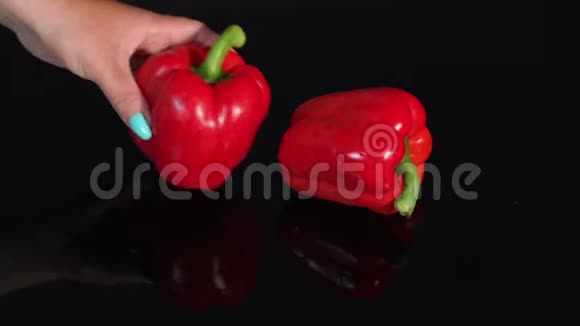 女孩把两个成熟多汁的红椒放在桌子上上面有一个黑色的镜子视频的预览图