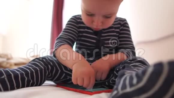 宝宝坐在床上玩智能手机动作缓慢视频的预览图