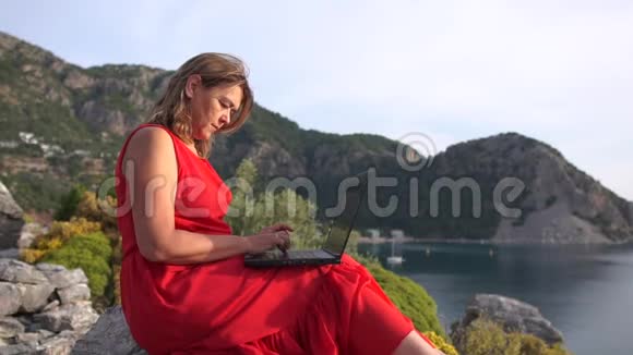 一个女人专注地在电脑上工作坐在高高的海面上动作缓慢视频的预览图