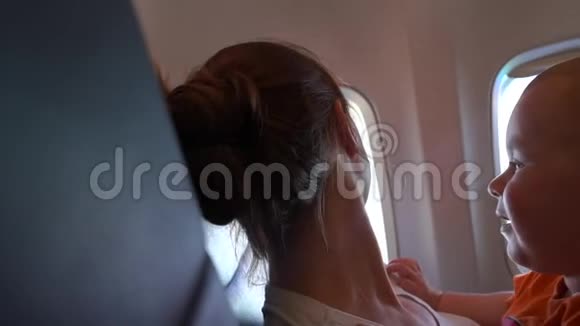 一个小孩在飞机上嬉戏地打妈妈的脸动作缓慢视频的预览图