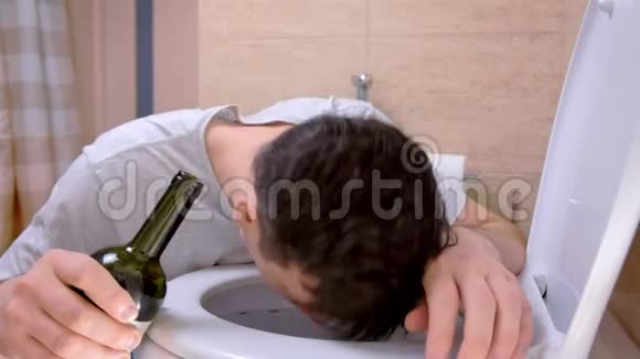 在厕所里恶心呕吐的男人手里拿着酒瓶感觉宿醉视频的预览图