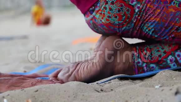 在海滩上做瑜伽特写女生双腿放在荷花位置模糊的背景供签名做运动普拉提伸展身体视频的预览图