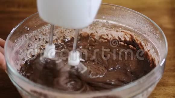 女性手的特写将水倒入巧克力面糊中视频的预览图