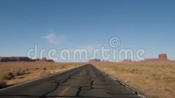 在阳光明媚的一天在纪念碑谷的热沙漠上驾车视频的预览图