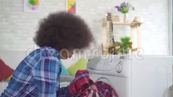 疲惫的非洲裔美国年轻妇女家庭主妇忙于家庭作业使用洗衣机视频的预览图