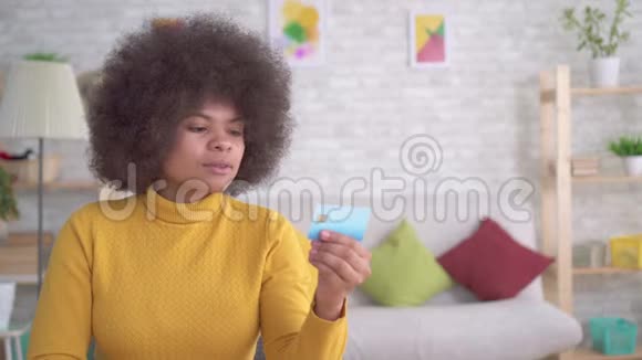 积极热情的美丽的非洲裔美国妇女她的发型是非洲式的她看着银行卡视频的预览图