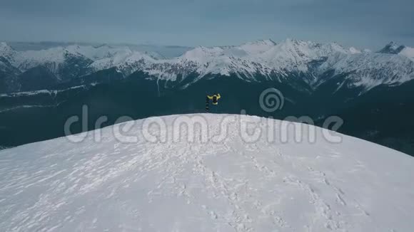 空中飞弹飞过胜利者雄雪板运动员欣赏岩石峰上的山景视频的预览图
